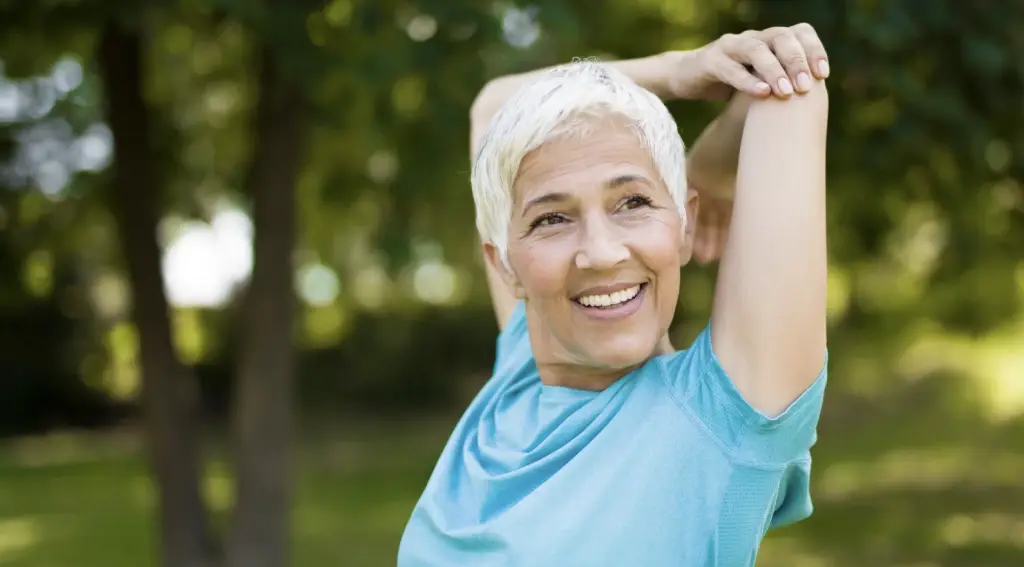 Older woman performing triceps stretch outdoors